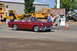 1959 Kenworth W900A - A classic red convertible drives past onlookers at an outdoor event.