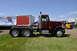 1959 Kenworth W900A - A red semi-truck tractor is parked on grass next to a trailer advertising a truck show.