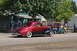 1959 Kenworth W900A - A classic red and black coupe drives past a golf cart at an outdoor event.