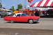 1959 Kenworth W900A - A classic red Ford Thunderbird is on display at an outdoor event with other vehicles and tents in the background.