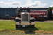 1959 Kenworth W900A - A vintage Peterbilt truck is displayed in front of a building with other vehicles.