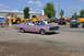 1959 Kenworth W900A - A pink 1966 Dodge Charger is seen driving on a road with other vehicles and buildings in the background.
