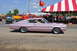 1959 Kenworth W900A - A pink 1966 Dodge Charger is seen at an outdoor event with a tent and emergency vehicles in the background.
