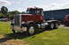 1959 Kenworth W900A - A classic Peterbilt 359 semi-truck is displayed outdoors with other vehicles in the background.
