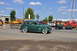 1959 Kenworth W900A - A green 1936 sedan is seen driving at an outdoor event with various construction and emergency vehicles in the background.
