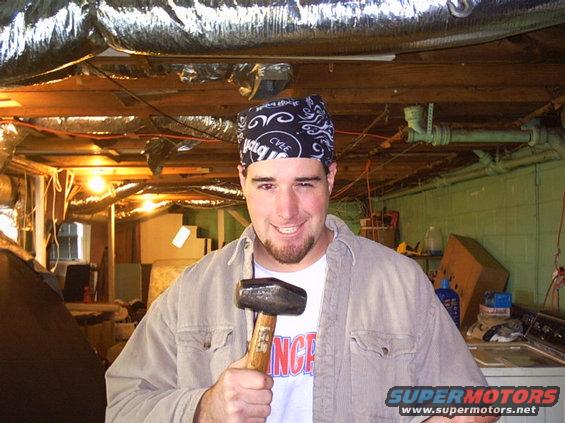 Man in bandana holding a sledgehammer in a basement