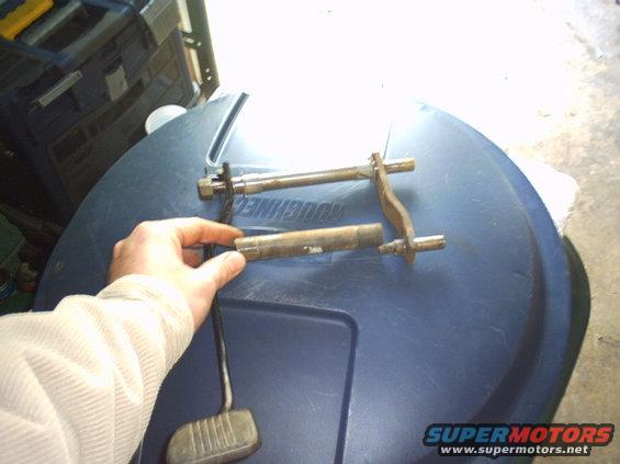 Metal pedal assembly components and a brake pedal on a blue surface