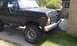 1979 Ford Bronco - A black Ford Bronco is parked outside a house, showing its front end and lifted suspension.