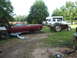 1966 Ford Ranchero - A red 1966 Ford Ranchero sits in a yard next to a tractor and other vehicles.