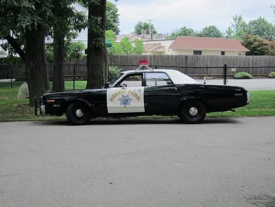 Side view of black and white police car with "HIGHWAY PATROL" emblem