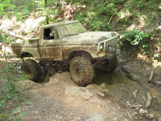 Muddy 1979 Ford F-150 navigating a rocky, wet trail