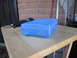 1963 Ford Falcon - A blue plastic container sits on a wooden table next to a rotary tool and a broom.