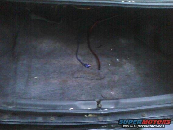 Car trunk interior with gray carpet and loose wires