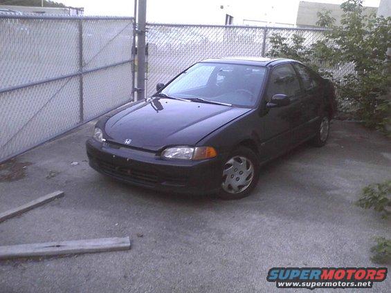 Black coupe parked on concrete, 3/4 front view
