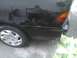 2003 Ford Crown Victoria - The rear passenger side of a black sedan is visible, with a gas cap door and part of a taillight.