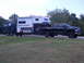1967 Ford Mustang - A black pickup truck tows a large camper and a buggy on a trailer.