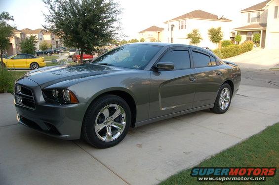 Gray sedan parked on driveway, yellow car in background