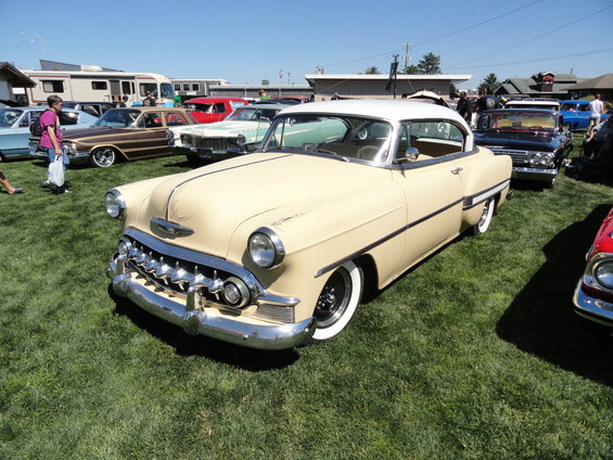 Tan and white 1954 Chevrolet Bel Air coupe with chrome grille and whitewall tires on display