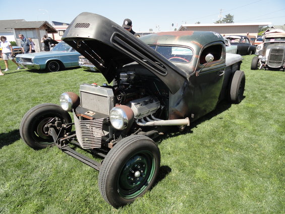 Hot rod pickup truck with hood open, showing engine, rusty patina, and custom front end