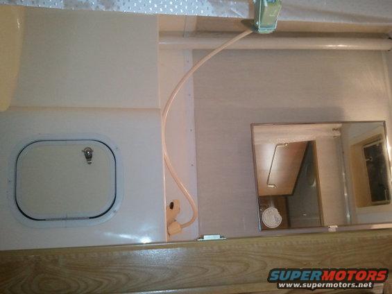RV interior with a closed access panel and a mirror reflecting cabinets