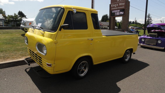 Yellow 1965 Ford Econoline pickup truck parked next to a purple pickup truck