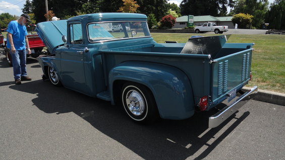 blue pickup truck with hood open, man standing nearby, another truck in background