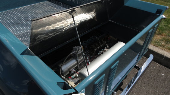 Blue truck bed interior with diamond plate flooring, air compressor, and tank
