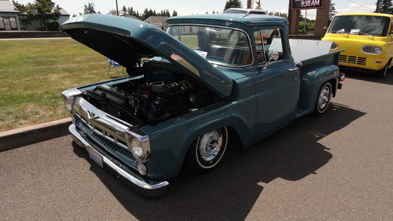 teal pickup truck, hood up showing engine, parked next to yellow van