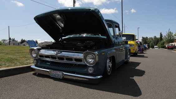 Blue 1956 Ford F-100 pickup truck with hood open, parked on street
