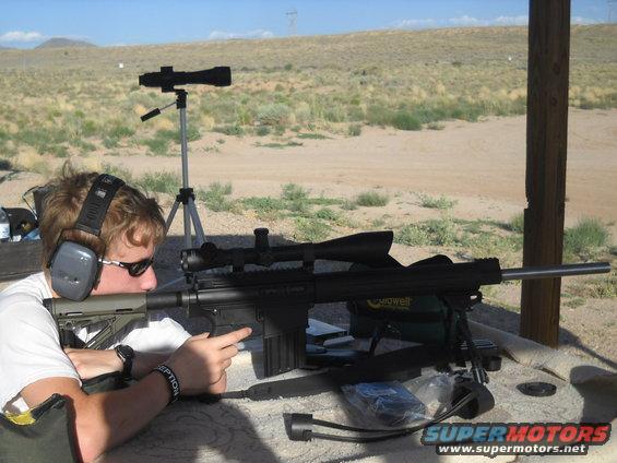 Sniper rifle with scope on bipod, shooter aiming