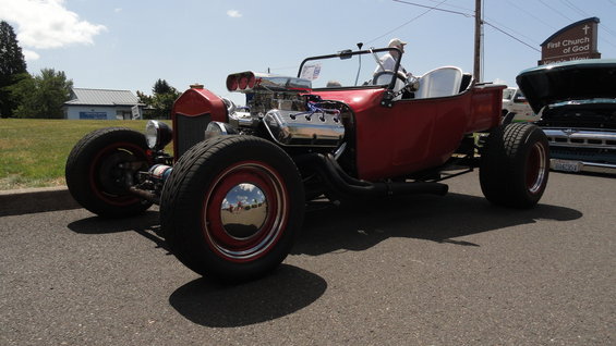 Red hot rod with exposed engine and chrome details, parked on asphalt