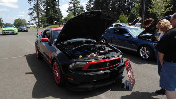 Black Ford Mustang with red accents and hood open, parked outdoors