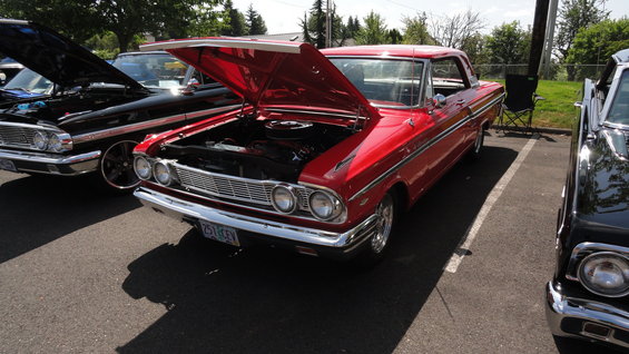 red classic car with hood open, parked next to a black car