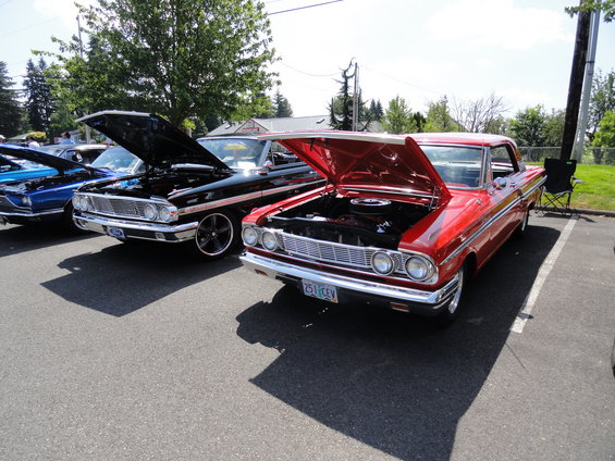 Red and black vintage Ford cars with hoods up parked in a lot