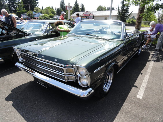 Green 1965 Ford Galaxie convertible parked next to another car