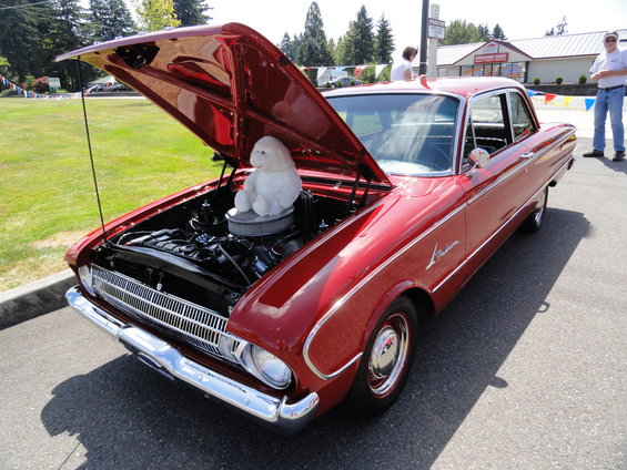 red sedan, hood open, showing engine and a white stuffed animal on top of the air cleaner