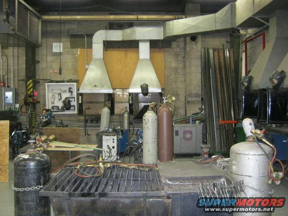 Welding shop interior with multiple gas cylinders, welding equipment, and metal stock