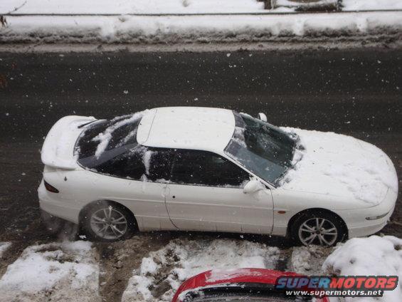 white 1995 Ford Probe covered in snow, parked on a snowy street
