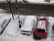 1995 Ford Probe - A person brushes snow off a white 1995 Ford Probe parked on a snowy street next to a red car.