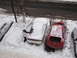 1995 Ford Probe - A person brushes snow off a white car while other vehicles are also covered in snow.