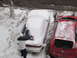 1995 Ford Probe - A person clears snow from the rear window of a white 1995 Ford Probe parked on a snowy street next to a red car.