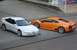 1995 Ford Probe - A white Ford Probe is parked next to a bright orange Lamborghini sports car on a city street.