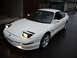1995 Ford Probe - A white Ford Probe is parked on a wet street, its headlights illuminated.