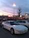 1995 Ford Probe - A white Ford Probe is parked in a lot with other vehicles under a dusky sky.