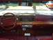 1991 Mercury Grand Marquis - The dashboard and steering wheel of a car are shown, wood grain accents and a maroon interior.