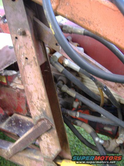 Close-up of hydraulic hoses and rusted metal frame on agricultural equipment