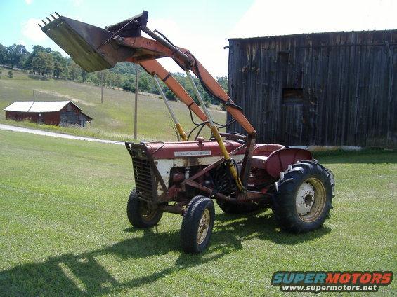 Red and white tractor with front loader parked in a grassy field