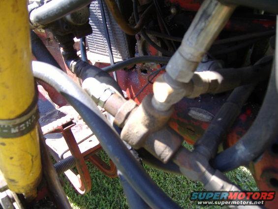 Close-up of hydraulic lines and engine parts with a yellow cylinder