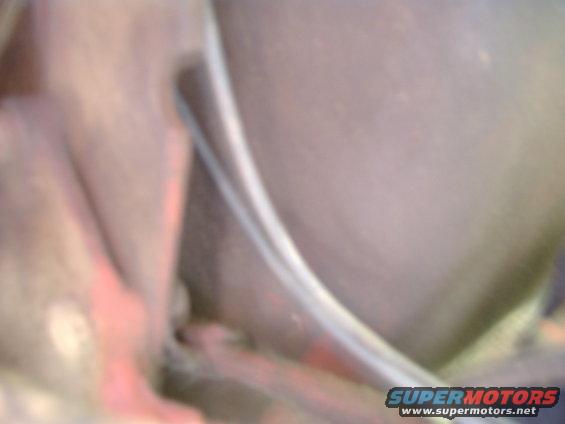 Close-up of a vehicle's interior with a curved metal trim piece and some red-colored components visible