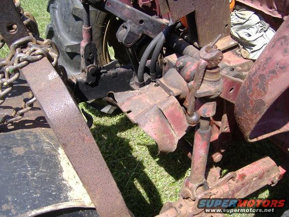 Red tractor rear hitch assembly with chains and hydraulic lines